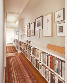 a long bookshelf filled with lots of books on top of a hard wood floor