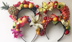 two mickey ears made out of fruit and flowers are shown on a white wall with butterflies