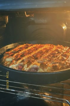 a pizza is cooking in an oven with the light shining on it's side