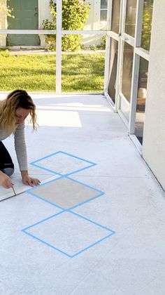 a woman is laying on the floor with blue tape around her legs and drawing squares