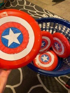 a hand holding a basket filled with red, white and blue plastic captain america balls