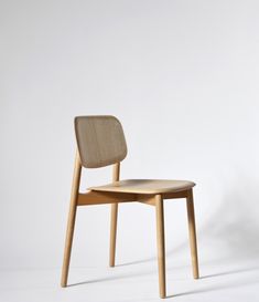 a wooden chair sitting on top of a white floor covered in light colored wood furniture