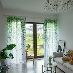 a living room filled with furniture and a window covered in green leaves next to a white couch