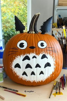 a pumpkin painted to look like an angry cat with big eyes and claws on it