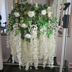 white flowers and greenery are hanging from a mirror