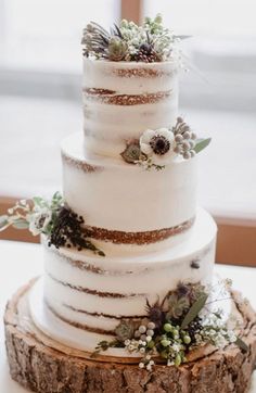 a three tiered white wedding cake with succulents and greenery on top