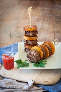 hamburgers and sweet potato rings on a plate with ketchup, sauce and napkin