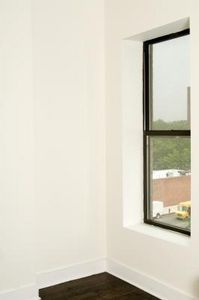 an empty room with white walls and wood flooring in front of a large window