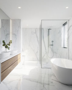 a large white bathroom with two sinks and a bathtub