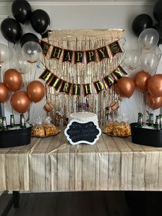 a table topped with lots of black and gold balloons, streamers and signs that say happy birthday