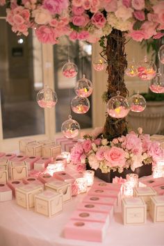 a table topped with lots of pink flowers next to boxes filled with small candies