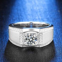 a white gold ring with a diamond center surrounded by pave diamonds on a blue background