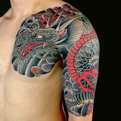 a man with a dragon tattoo on his arm and chest is standing in front of a black background