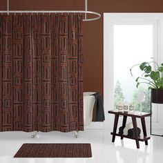 a bathroom with a shower curtain, rug and table in front of the door that has a potted plant on it