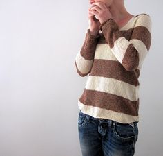 a woman standing in front of a white wall with her hands clasped to her chest