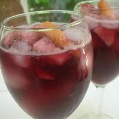 two glasses filled with red liquid and garnished with orange peels