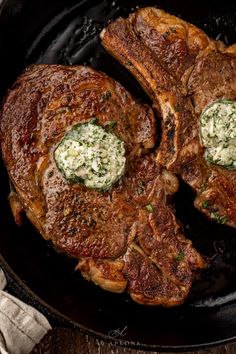 two steaks are being cooked in a skillet with butter and herbs on top