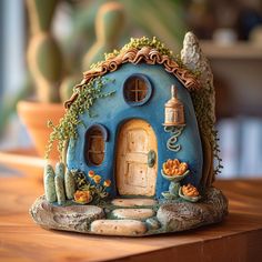 a small blue house sitting on top of a wooden table next to a potted plant