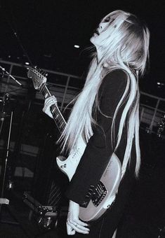 a woman with long blonde hair playing an electric guitar