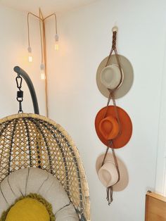 hats are hanging on the wall next to a wicker chair