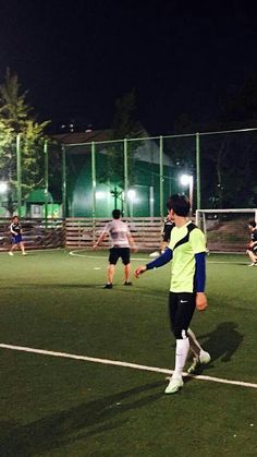 a group of people playing soccer on a field at night with lights in the background