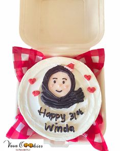 a cake with a woman's face on it in a plastic container and red ribbon