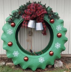 a green wreath with snowflakes and christmas decorations on the front is hanging from a wall