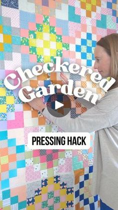 a woman standing in front of a colorful quilt with the words checkered garden on it