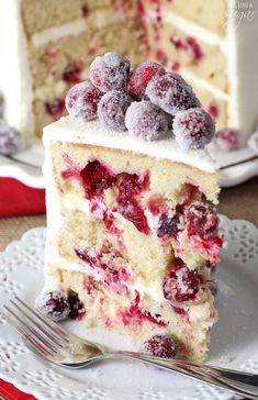 a cake with white frosting and berries on top is cut in half to show the inside