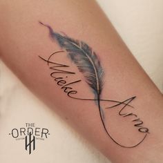 a woman's arm with a feather and the word love written in cursive writing