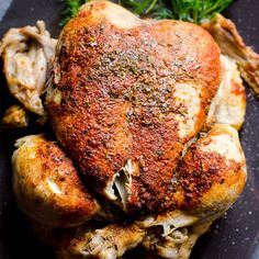 a whole chicken on a black plate with parsley