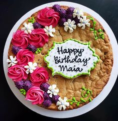 a birthday cake decorated with flowers and the words happy birthday maai on it's side