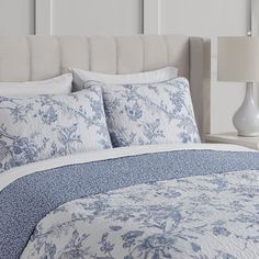 a bed with blue and white comforters in a bedroom next to a night stand