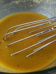 the whisks are being stirred in the bowl with orange liquid and sugar on top