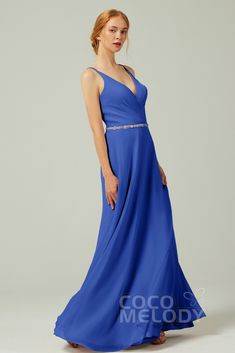 a woman in a long blue dress posing for the camera with her hands on her hips