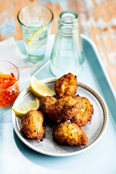 some food is sitting on a plate with lemon wedges and a glass of water