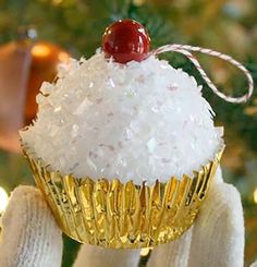 a cupcake ornament with a cherry on top in front of a christmas tree