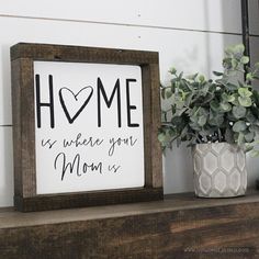 a sign that says home is where you mom is next to a potted plant