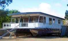 a house boat sitting on top of a body of water next to a dock with stairs leading up to it