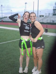 two girls posing for the camera with their arms around each other on a soccer field