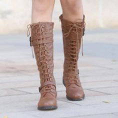 a woman is wearing brown boots with laces on the side and her legs crossed