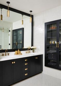 a black and white bathroom with gold accents on the sink, mirror and cabinets in front of it