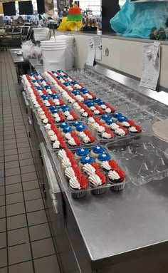 cupcakes with red, white and blue frosting are lined up on a conveyor belt