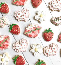 decorated cookies are arranged on a white table with flowers, hearts and strawberries in the center