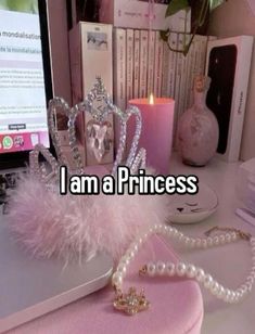 a princess tiara sitting on top of a desk next to a laptop computer and candle