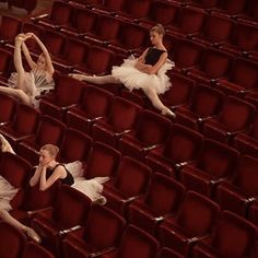 three ballerinas in white tutus and black leotards sitting on red seats