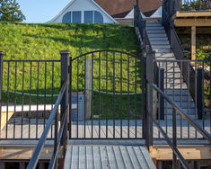 an outdoor stairway leading to a house with a green lawn on the hill behind it