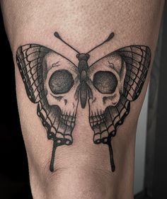 a black and white photo of a butterfly tattoo on the leg, with a skull in the middle