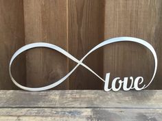 a metal sign with the word love on it sitting on a wooden table next to a wall