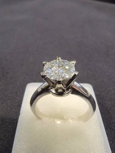 a diamond ring sitting on top of a white stand